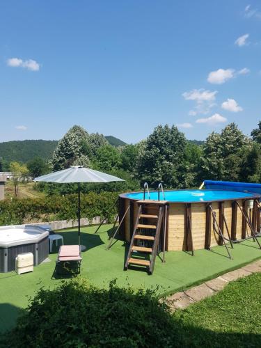 ein großer Pool mit Leiter und Sonnenschirm in der Unterkunft Стаи за гости ''Живел'' in Oreshak