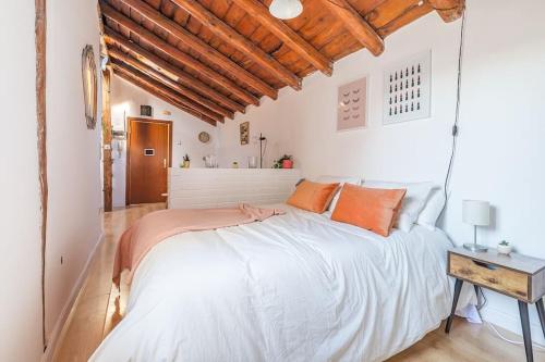 1 dormitorio con 1 cama blanca grande con almohadas de color naranja en Maravilloso estudio en Chamberi. Metro Quevedo en Madrid