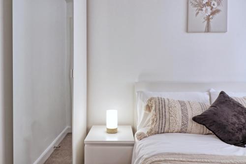 a white bedroom with a bed with a candle on a night stand at Hythe Hill Home in Colchester