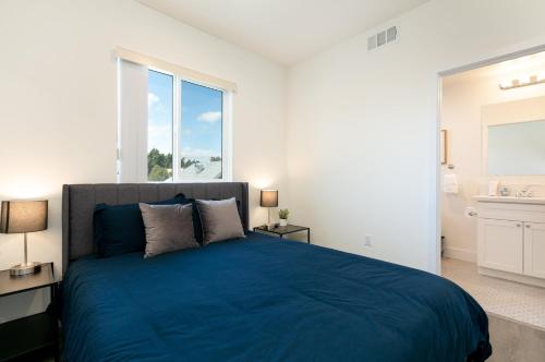 a bedroom with a blue bed and a large window at Downtown Darling by AvantStay Rooftop Deck View in Los Angeles