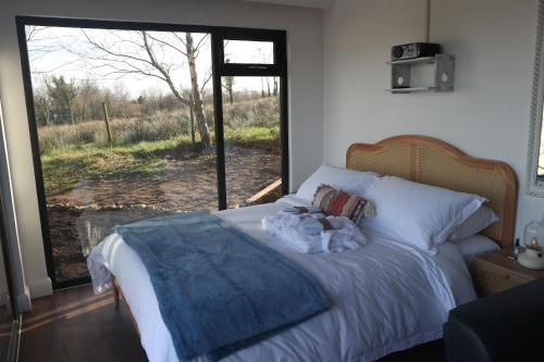a bedroom with a bed and a large window at LakEscape - Waterfront Self- Catering Cabins in Enniskillen