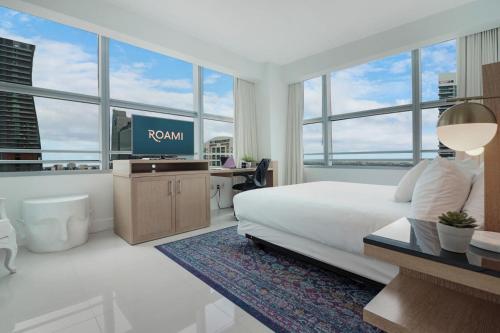 a hotel room with a bed and a tv and windows at Roami at Brickell Penthouse Luxe Loft in Miami