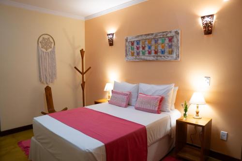 1 dormitorio con 1 cama grande con almohadas rosas en Pousada Lua Clara, en Alto Paraíso de Goiás