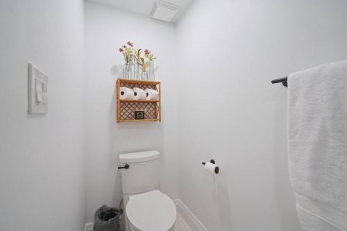 a white bathroom with a toilet and a shelf on the wall at Spanish Fork Retreat in Spanish Fork