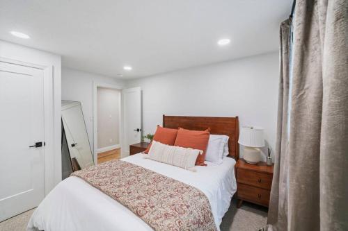 Schlafzimmer mit einem Bett mit weißer Bettwäsche und orangefarbenen Kissen in der Unterkunft Spanish Fork Retreat in Spanish Fork