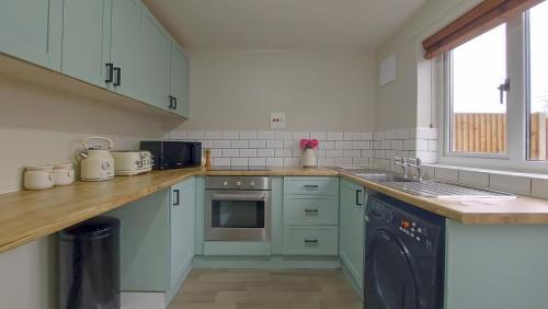 a kitchen with blue cabinets and a sink at 2BD Home: Locale Near Old Town & Fast London Links in Stevenage