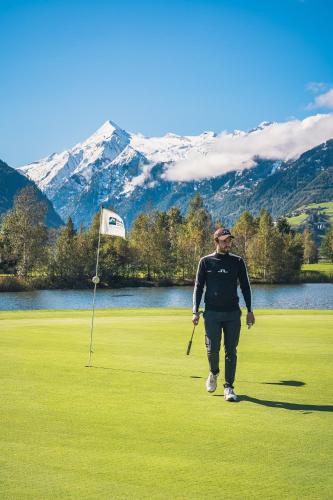 a man walking on a golf course with a club at Der Schütthof in Zell am See
