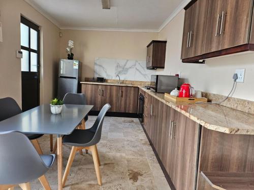 una cocina con armarios de madera, mesa y sillas en 11 Reservoir Road, en Queenstown