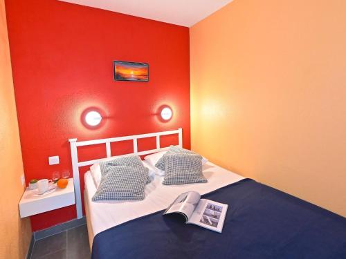 - une chambre avec des murs rouges et un lit avec un livre dans l'établissement Apartment Le Hameau - L2 002 by Interhome, à Agay