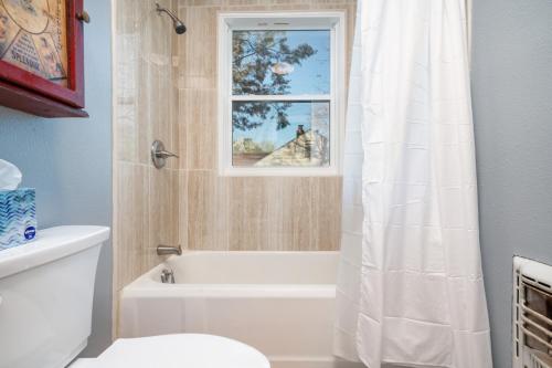 baño con bañera, aseo y ventana en Doras Dutch Cottage Charmer with Swimming Pool, en Clarksville