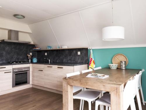 een keuken met een houten tafel en witte kasten bij Holiday Home Emslandermeer by Interhome in Vlagtwedde