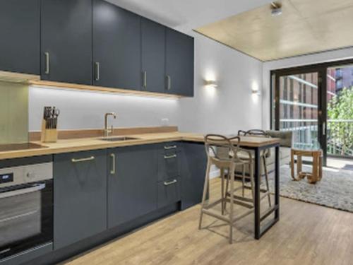 a kitchen with blue cabinets and a table and chairs at Apartment Wembley Park apartments-1 by Interhome in London