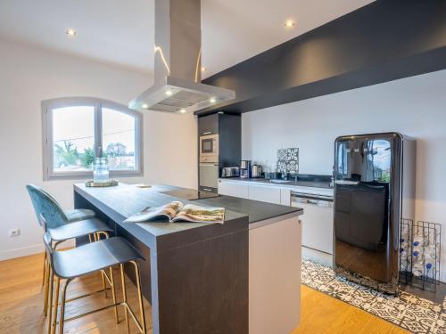 La cuisine est équipée d'un grand îlot avec des chaises et un réfrigérateur. dans l'établissement Apartment Dade-3 by Interhome, à La Teste-de-Buch
