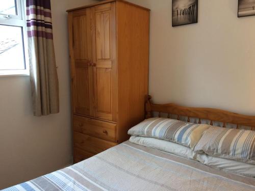 1 dormitorio con 1 cama y armario de madera en Cosy Cornish cottage with rural views, en Newquay