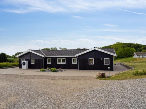 a black house with a gravel driveway at Holiday Home Edo - 575m from the sea in Funen by Interhome in Spodsbjerg