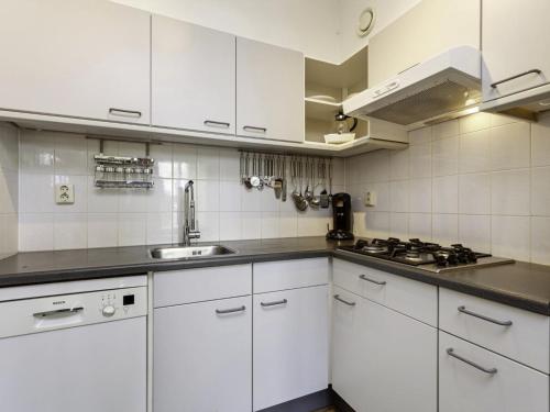 Una cocina con gabinetes blancos y un fregadero. en Holiday Home Bellingwolde Comfort by Interhome, en Vlagtwedde
