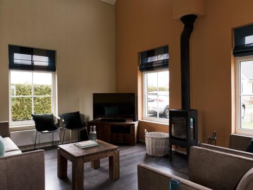 a living room with a couch and a tv and two windows at Holiday Home Heerd Wellness de Luxe by Interhome in Vlagtwedde