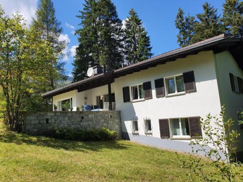 Casa blanca con ventanas negras y pared de piedra. en Apartment Ferienhaus Tina by Interhome, en Lenzerheide