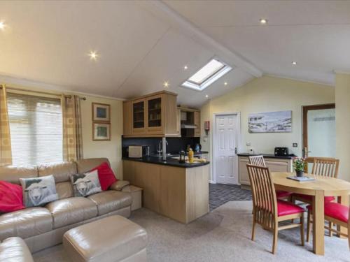 een woonkamer en een keuken met een bank en een tafel bij Chalet Windermere Lodge by Interhome in Windermere