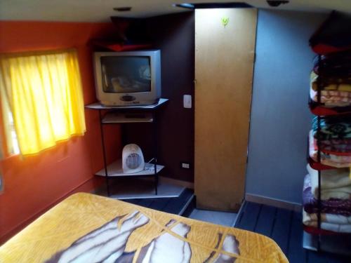 a room with a bed and a tv on a wall at Cabaña Bus LUYHANE in Yala