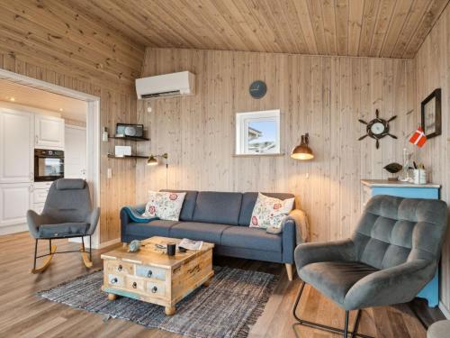 a living room with a blue couch and two chairs at Holiday Home Gyrid - 150m from the sea in Djursland and Mols by Interhome in Rønde