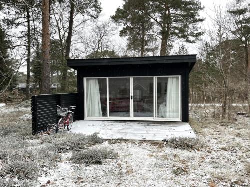 a small black house with a bike parked in a field at Holiday Home Giertrud - 1-1km from the sea in Sealand by Interhome in Vig