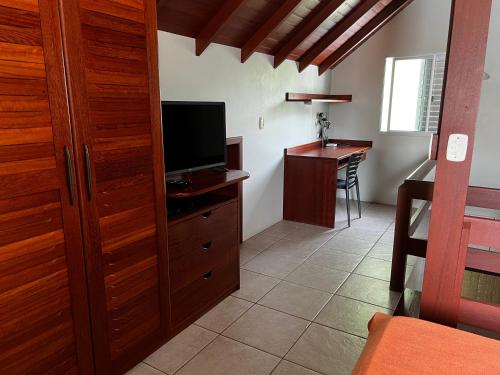 - un salon avec une télévision et un bureau dans l'établissement Pousada Residência Nativa, à Pinheira