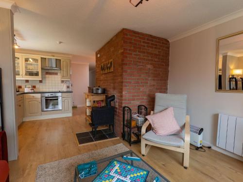 a living room with a brick fireplace and a chair at Holiday Home Stable Cottage by Interhome in Drumnadrochit