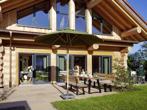 a patio with a table and a green umbrella at Chalet Schwarzwaldchalet de luxe mit Sauna by Interhome in Heitersheim