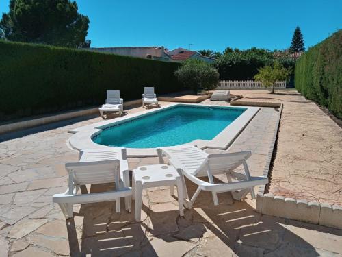 a swimming pool with two chairs and a table and two lawn chairs at Villa Solete by Interhome in L'Ametlla de Mar