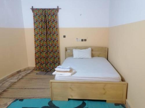 Le Jardin de L'Atacora في Natitingou: غرفة نوم صغيرة بسرير وستارة