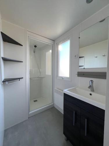 une salle de bain blanche avec un lavabo et une douche dans l'établissement mobilhome grand confort 6 couchages Cap Ferret, à Lège-Cap-Ferret