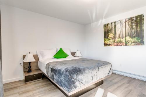 Dormitorio blanco con cama con almohada verde en Motel Saint Bruno, en Saint-Bruno-de-Montarville