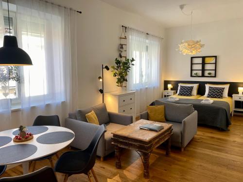 Boennium Apartments في ليوبليانا: غرفة معيشة مع سرير وطاولة وكراسي