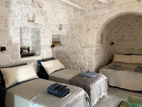 - 2 lits dans une chambre avec un mur en pierre dans l'établissement Trullanto, à Francavilla Fontana