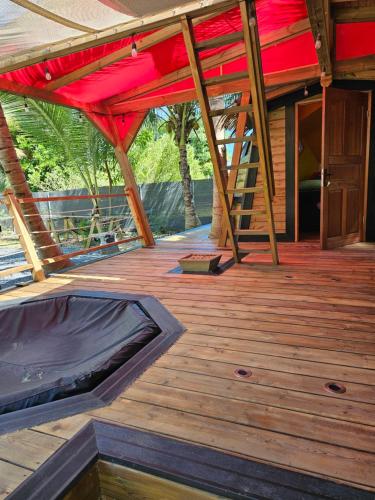 a hot tub on a wooden deck with a roof at Bungalow Ti Koko in Le Gosier