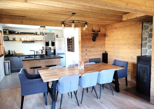 une salle à manger avec une table en bois et des chaises bleues dans l'établissement Chalet Mondego, paisible et tout confort, à Gérardmer