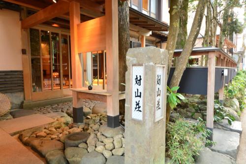 a building with a sign in the middle of a garden at AKARI et KAORI formerly Taizanso in Izu