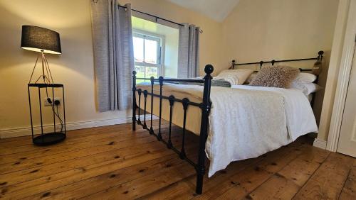 sypialnia z łóżkiem, lampką i oknem w obiekcie The Home House w mieście Plumb Bridge