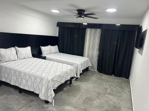 a bedroom with two beds and a ceiling fan at HOTEL and Suites Cananea in Cananea