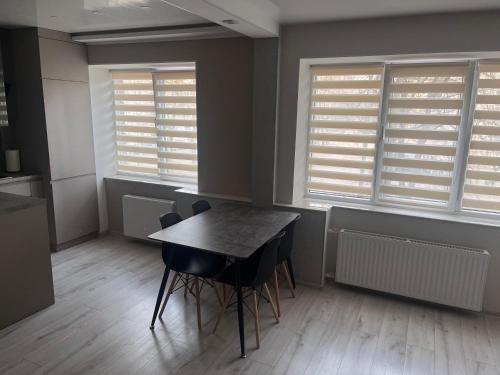 a dining room with a table and chairs and windows at ZE Apartments in Rēzekne