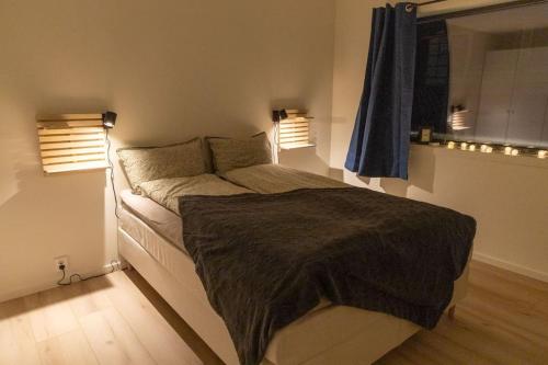 een slaapkamer met een groot bed en 2 ramen bij Helsesenterveien 7N in Haugland