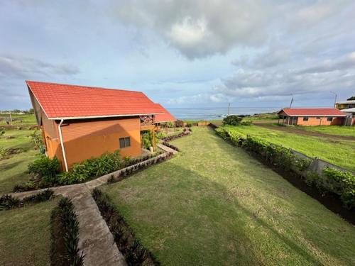 a small house with a red roof in a field at Cabañas Anavai Rapa Nui in Hanga Roa