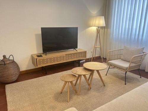 uma sala de estar com televisão e uma cadeira e mesas em 2Room Cozy Apartment Center Caparica em Costa da Caparica