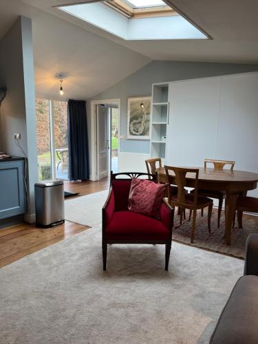 een woonkamer met een rode stoel en een tafel bij Villa de Nachtegaal in Naarden