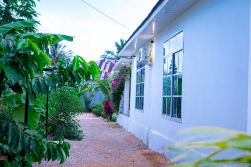 a sidewalk next to a white building with plants at Blossom House Zanzibar in Kitongani