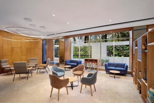 a waiting room with chairs and tables and windows at Holiday Inn Express Bengaluru Bommasandra by IHG in Bengaluru