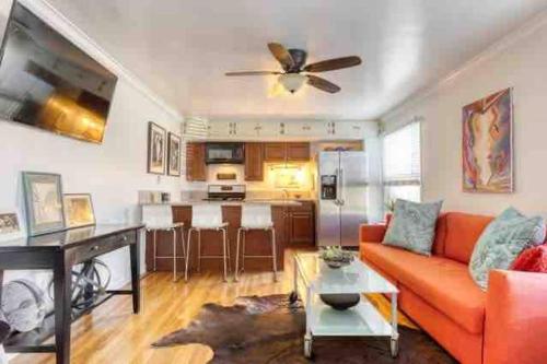 a living room with an orange couch and a kitchen at Belmont Shore Beach Bungalow, 2 min walk to town! in Long Beach