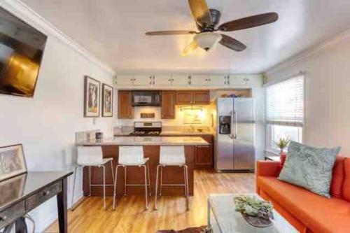 a living room with an orange couch and a kitchen at Belmont Shore Beach Bungalow, 2 min walk to town! in Long Beach