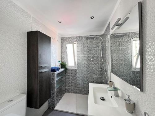 La salle de bains blanche est pourvue d'un lavabo et d'une douche. dans l'établissement Mirador La Galera, junto a la playa, à Candelaria